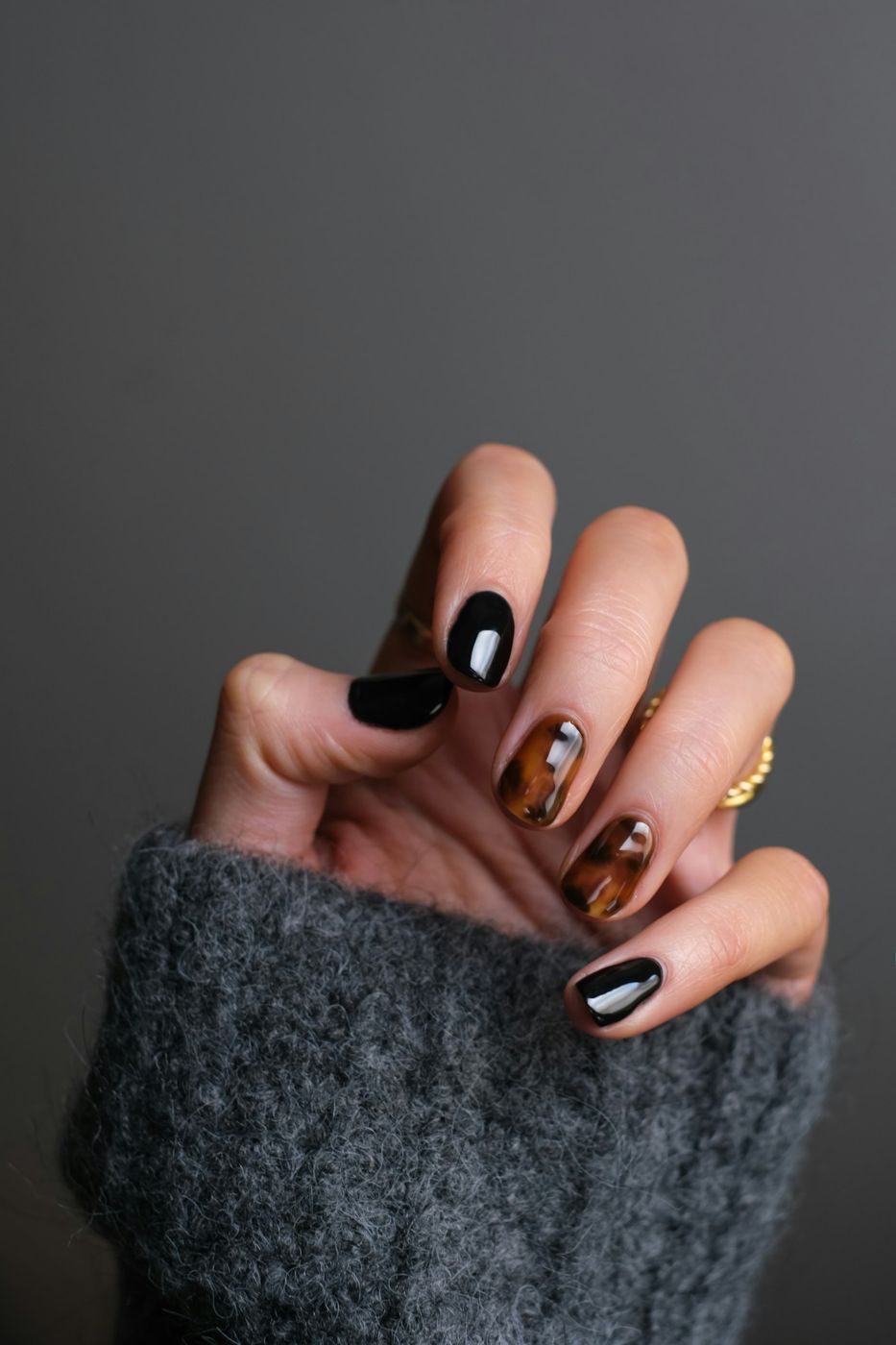 Imagen de referencia: mano con uñas decoradas en negro y dorado